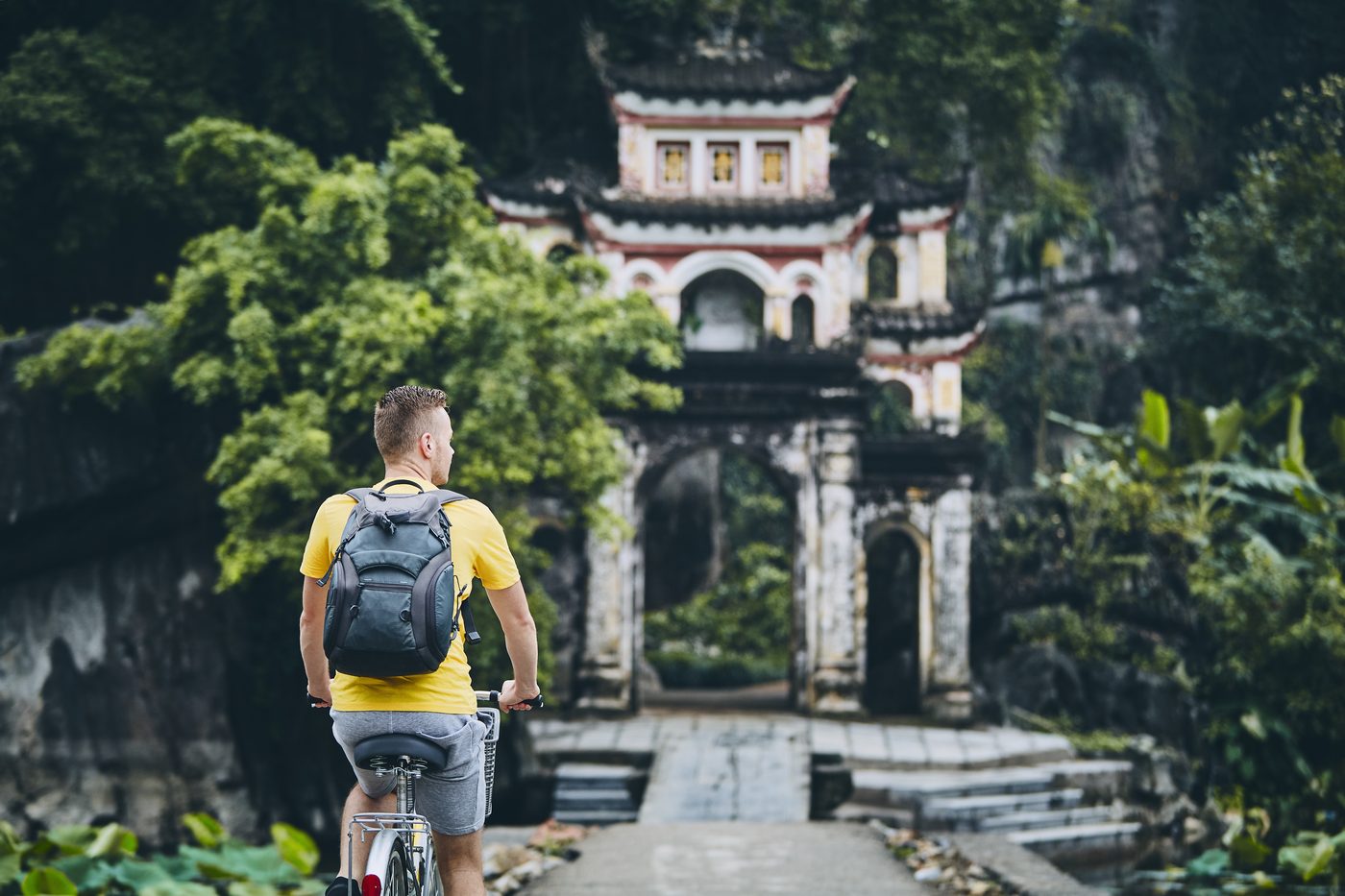 Traveler cycling toward a traditional Vietnamese temple gate, representing e-visa and entry documentation